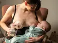 Kobieta karmi piersią dziecko, jednocześnie używając laktatora Tommee Tippee do odciągania mleka.