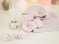 Szklana butelka Lovi z motywem Paryża, obok różowe skarpetki, czapeczka i smoczki.