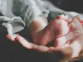 Delikatne stópki dzidziusia w dłoni, otulone miękkim kocykiem. Do prania ubranek użyto płynu do prania dzidziuś.