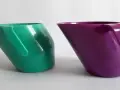 Dwa kubki doidy cup: zielony i fioletowy, stojące obok siebie na białym tle.