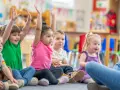 Dzieci na zajęciach w przedszkolu, z podniesionymi rękami. Czy z owsikami można iść do przedszkola? Nie, w przypadku owsików dziecko powinno zostać w domu.
