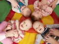 Uśmiechnięte dzieci na kolorowej macie. Czy żłobek jest dobry dla dziecka? Wiele maluchów wesoło bawi się z opiekunami.