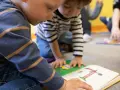 Dzieci uczą się i bawią razem, czytając książkę. To pokazuje, czy warto dać dziecko do żłobka.