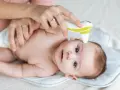 Mama mierzy temperaturę czoła niemowlaka termometrem bezdotykowym. To szybki sposób, gdzie mierzyć temperaturę u niemowlaka.