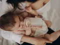 Dziecko pije z butelki przypominającej pierś. Mama czule trzyma butelkę, zapewniając maluchowi komfort.