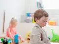 Chłopiec w szelkach i dziewczynka bawią się zabawkami. Zastanawiasz się, jak zapisać dziecko do żłobka?