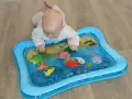 Niemowlę bawi się na dmuchanej macie wodnej z morskimi zwierzątkami. Kolorowa zabawka zachęca do odkrywania podwodnego świata.