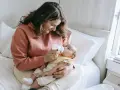 Mama karmi dziecko butelką, używając miarki do mleka modyfikowanego.