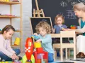 Dzieci budują rakietę z klocków, a opiekunka czuwa. Ciekawe, ile zarabia opiekunka w żłobku za taką pracę.
