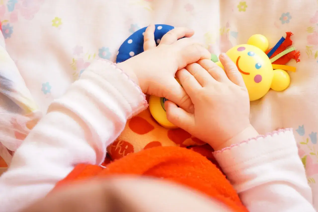 Małe rączki bawią się kolorowymi zabawkami. Dziecko odkrywa świat, a "a kuku zabawki" towarzyszą mu w tej przygodzie.