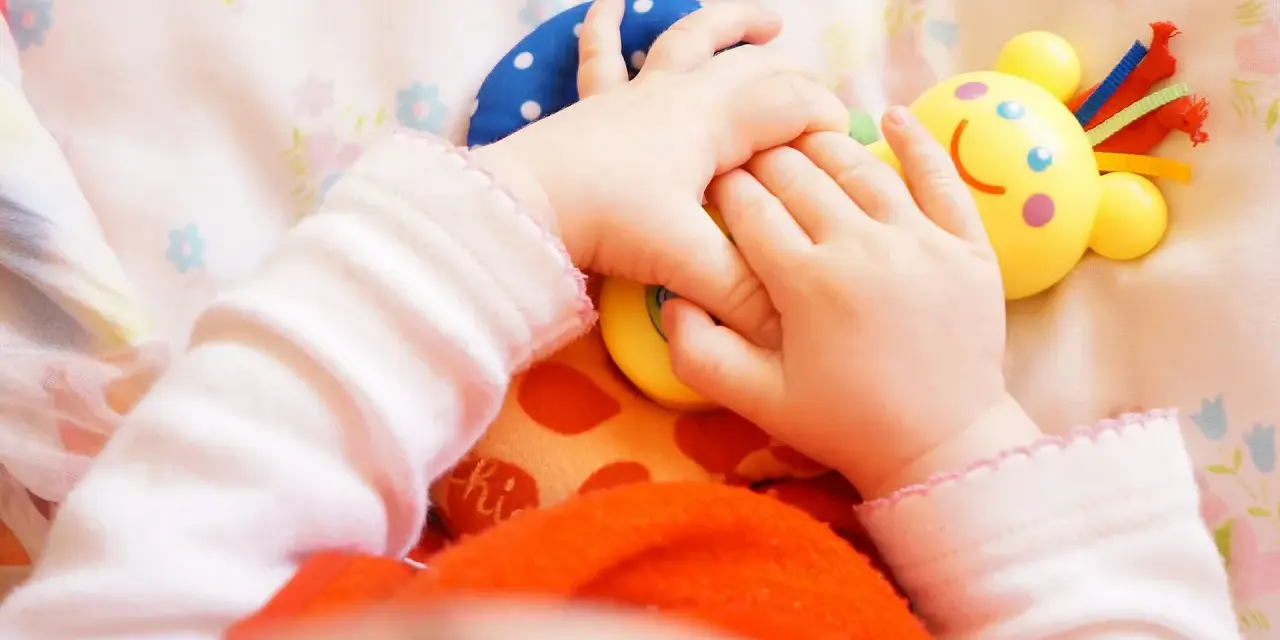 Małe rączki bawią się kolorowymi zabawkami. Dziecko odkrywa świat, a "a kuku zabawki" towarzyszą mu w tej przygodzie.