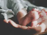 Delikatne stópki dzidziusia w dłoni, otulone miękkim kocykiem. Do prania ubranek użyto płynu do prania dzidziuś.