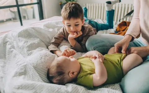 Starszy brat patrzy z czułością na niemowlę, zastanawiając się, ile niemowlę rośnie w miesiąc.