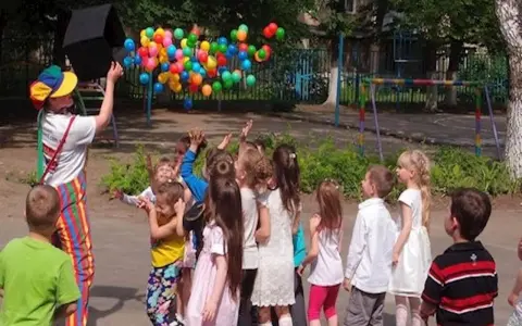 Klaun wypuszcza balony dla dzieci. Czy są zerówki w szkołach? Dzieci cieszą się zabawą na świeżym powietrzu.