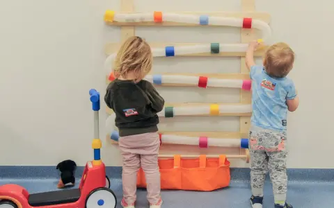 Dzieci bawią się w żłobku, gdzie można zapisać dziecko do żłobka w trakcie roku. Zabawki i ściana sensoryczna.