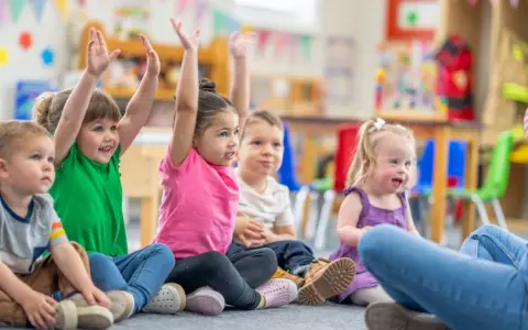 Dzieci na zajęciach w przedszkolu, z podniesionymi rękami. Czy z owsikami można iść do przedszkola? Nie, w przypadku owsików dziecko powinno zostać w domu.