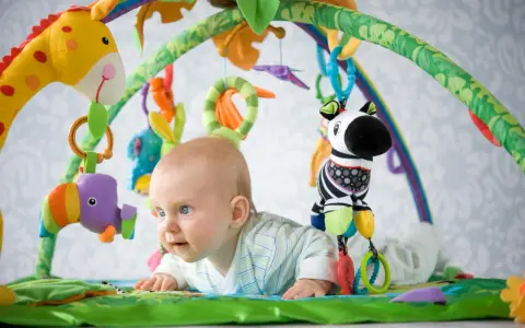 Maluch odkrywa świat na kolorowej macie edukacyjnej dla dzieci. Wesołe zabawki zachęcają do zabawy.