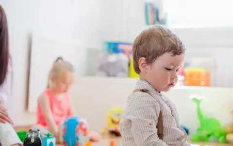 Chłopiec w szelkach i dziewczynka bawią się zabawkami. Zastanawiasz się, jak zapisać dziecko do żłobka?