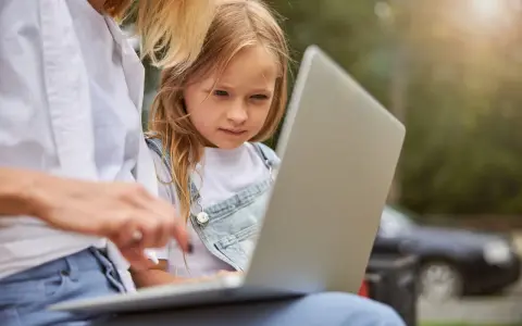 Mama z córką przeglądają internet, szukając informacji, kiedy jest rekrutacja do żłobka.