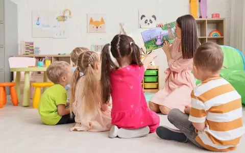 Nauczycielka czyta dzieciom bajkę. W przedszkolu bezpłatnych godzin jest 5.