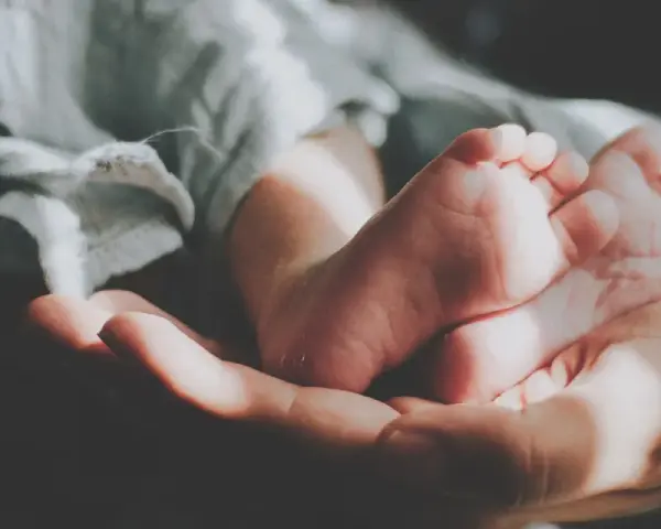 Delikatne stópki dzidziusia w dłoni, otulone miękkim kocykiem. Do prania ubranek użyto płynu do prania dzidziuś.