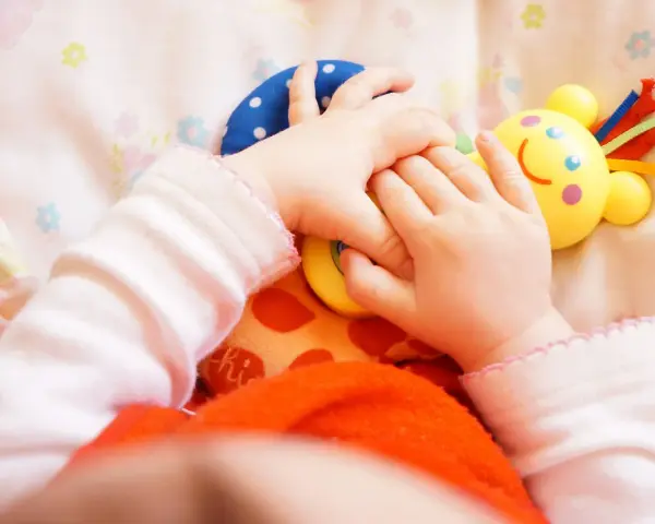 Małe rączki bawią się kolorowymi zabawkami. Dziecko odkrywa świat, a "a kuku zabawki" towarzyszą mu w tej przygodzie.