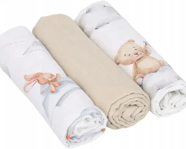 Trzy zwinięte babyono pieluszki muślinowe: dwie z motywem misia i królika, jedna gładka, beżowa.