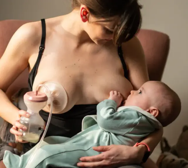 Kobieta karmi piersią dziecko, jednocześnie używając laktatora Tommee Tippee do odciągania mleka.