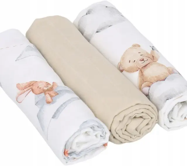 Trzy zwinięte babyono pieluszki muślinowe: dwie z motywem misia i królika, jedna gładka, beżowa.