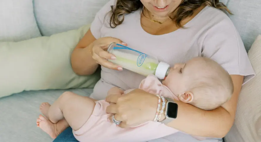 Kiedy zmienic przeplyw smoczka? Mama karmi dziecko butelką, obserwując, czy maluch nie ma problemów z jedzeniem.