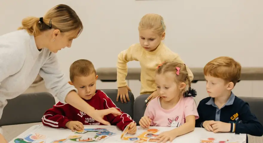 Nauczycielka pomaga dzieciom układać obrazki. Czy przedszkole może wypisać dziecko? Dzieci uczą się przez zabawę.