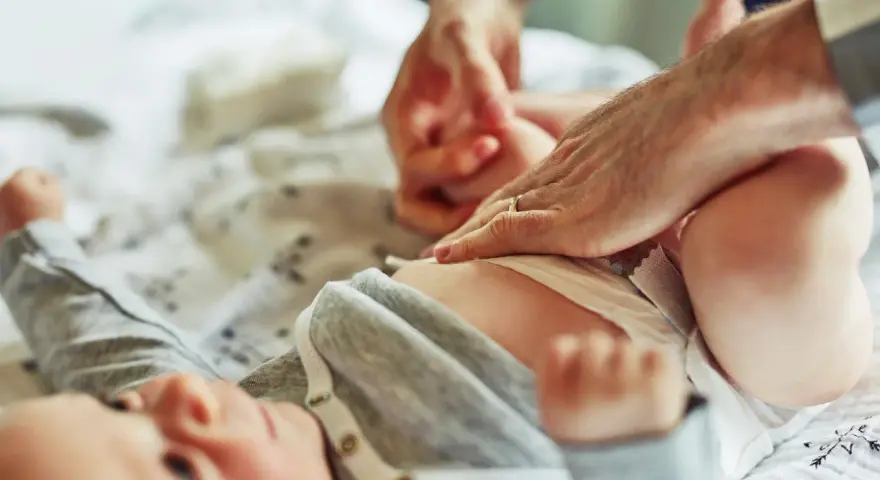 Rodzic zmienia pieluchę noworodkowi. Ile pieluch na miesiąc dla noworodka? To pytanie nurtuje wielu rodziców.