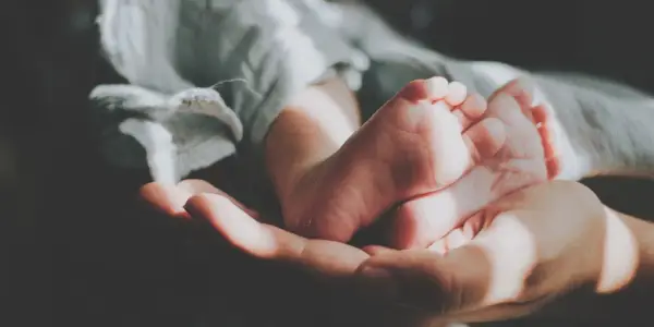 Delikatne stópki dzidziusia w dłoni, otulone miękkim kocykiem. Do prania ubranek użyto płynu do prania dzidziuś.