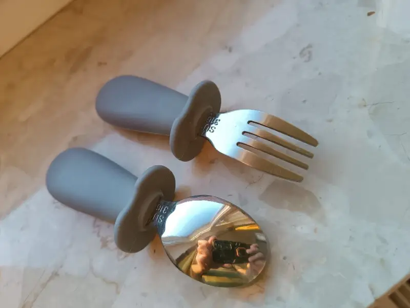 Szare, ergonomiczne pierwsze sztućce dla dzieci: łyżka i widelec. Idealne do nauki samodzielnego jedzenia.
